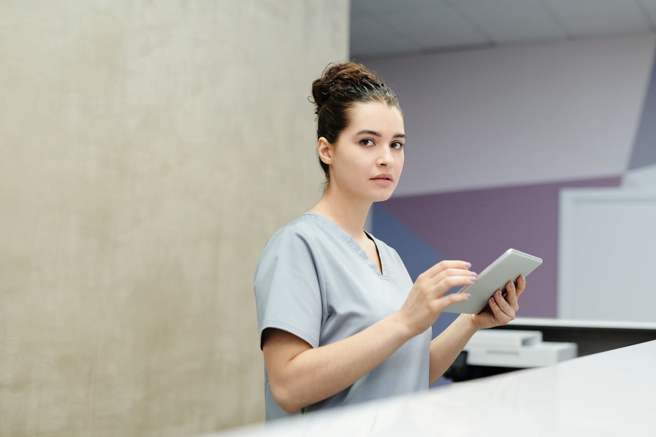Professional receptionist using a tablet device at a modern office reception desk.