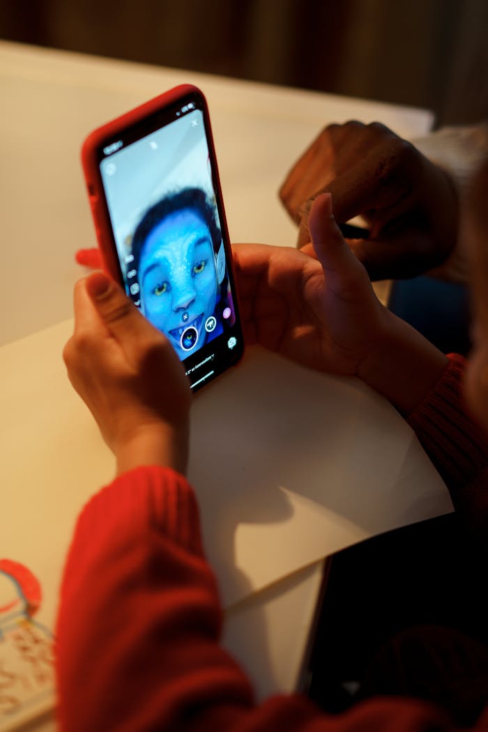 A child uses a smartphone with a fun facial filter, indoors, showcasing modern technology and creativity.